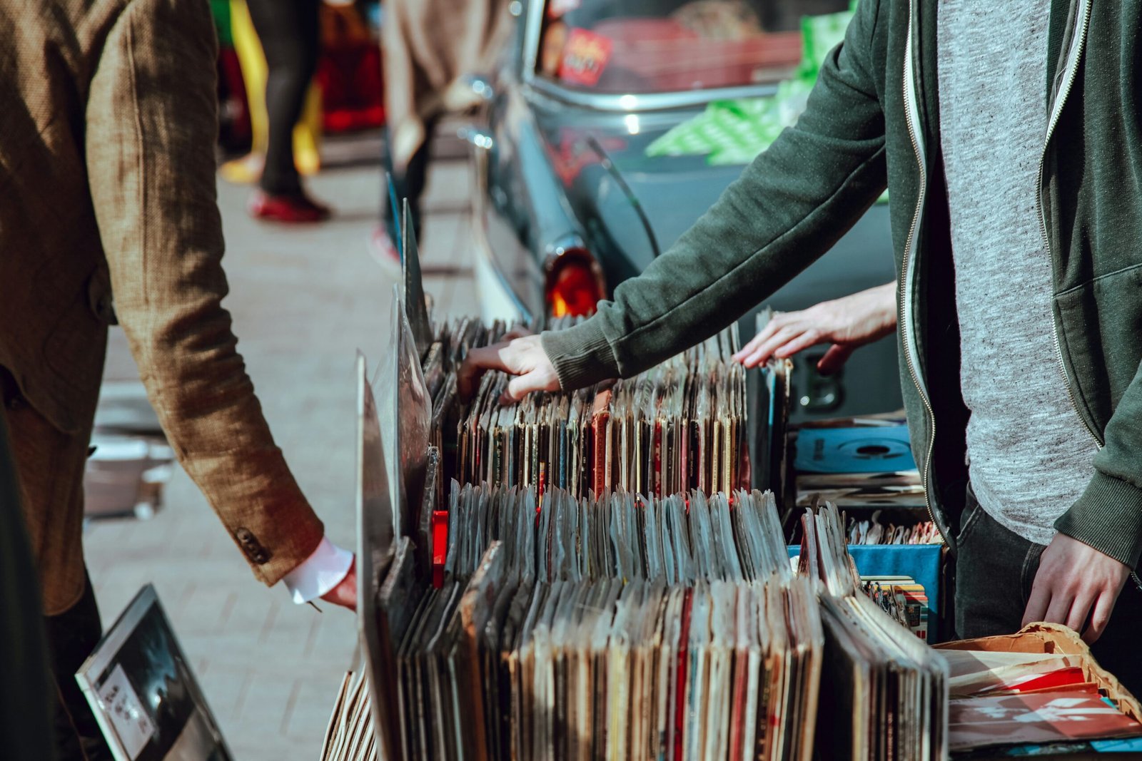 People flipping through crates of vinyl records at an outdoor record fair