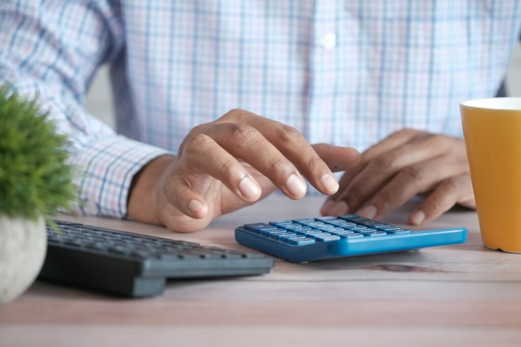 Person using a calculator at a desk to work out taxes