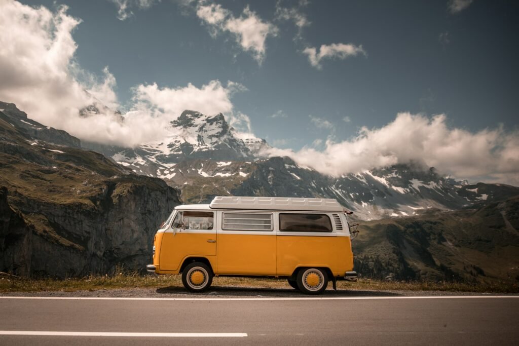 Orange and white camper van on a mountain pass road in the Alps