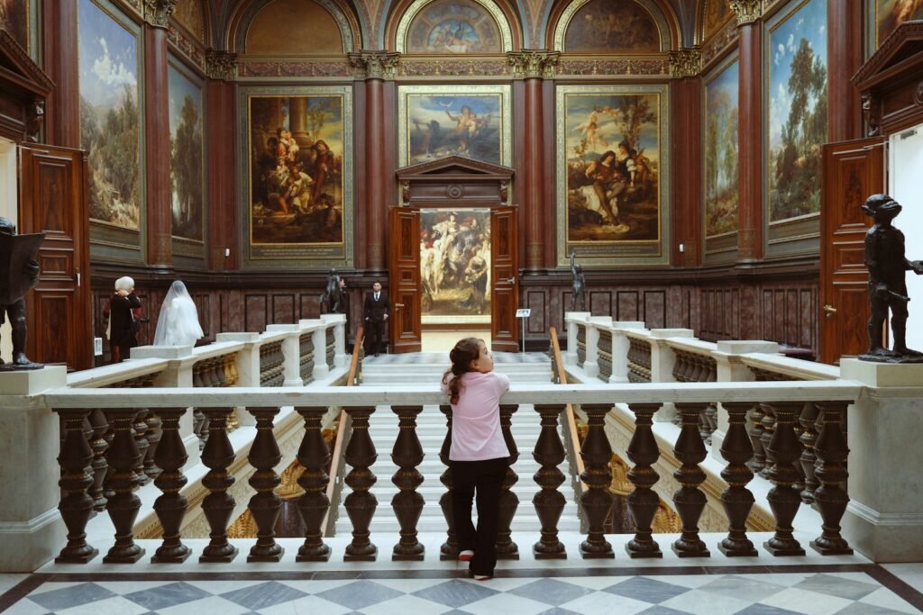 Person looking at paintings in a grand hall