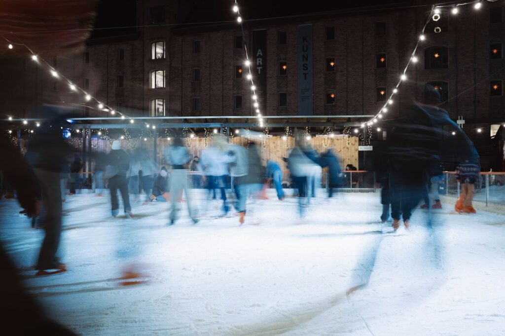 People ice skating at night under string lights