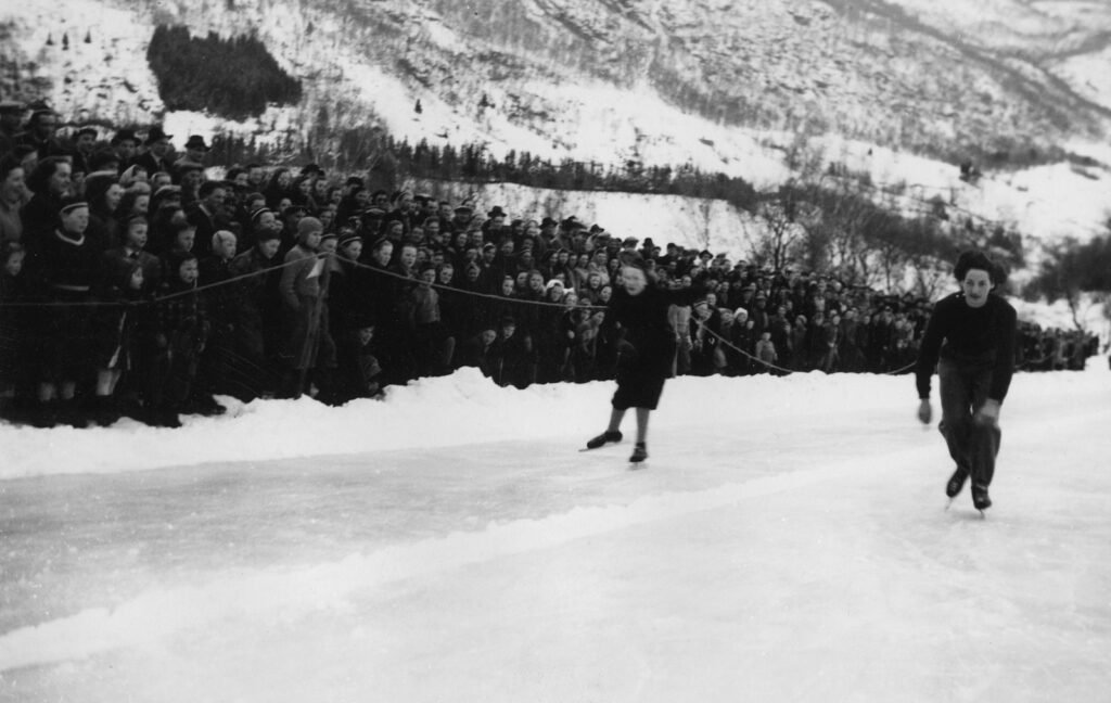 Skaters racing on an ice track with spectators