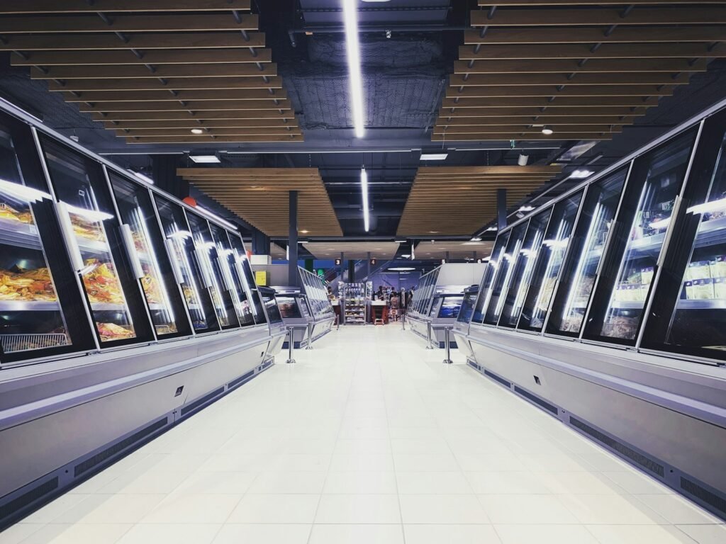 Empty supermarket freezer aisle with glass-door fridges and freezers on both sides