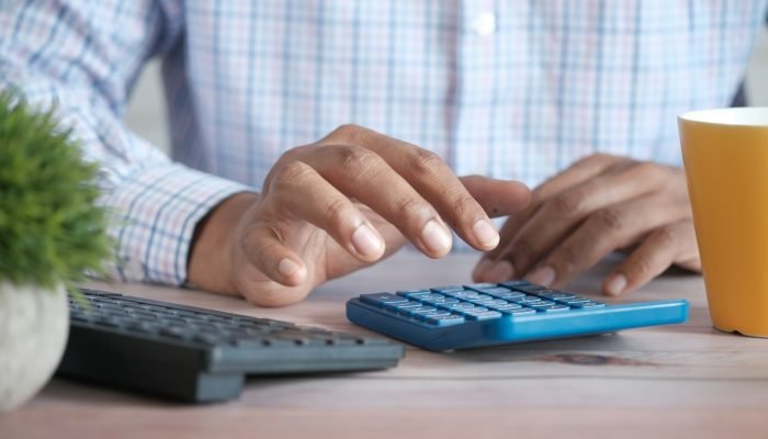 Person using a calculator at a desk to work out taxes
