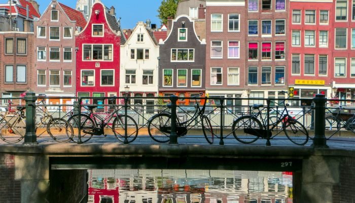 Historic canal houses in Amsterdam with bicycles parked on a bridge