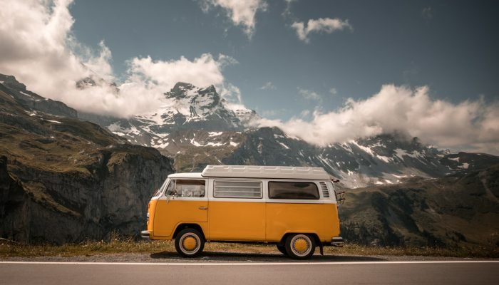 Orange and white camper van on a mountain pass road in the Alps